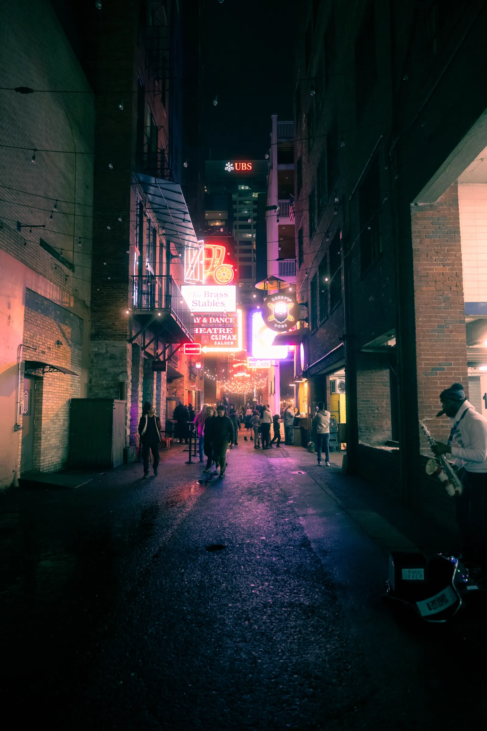 A narrow New Orleans street glowing with neon and theatre lights at night