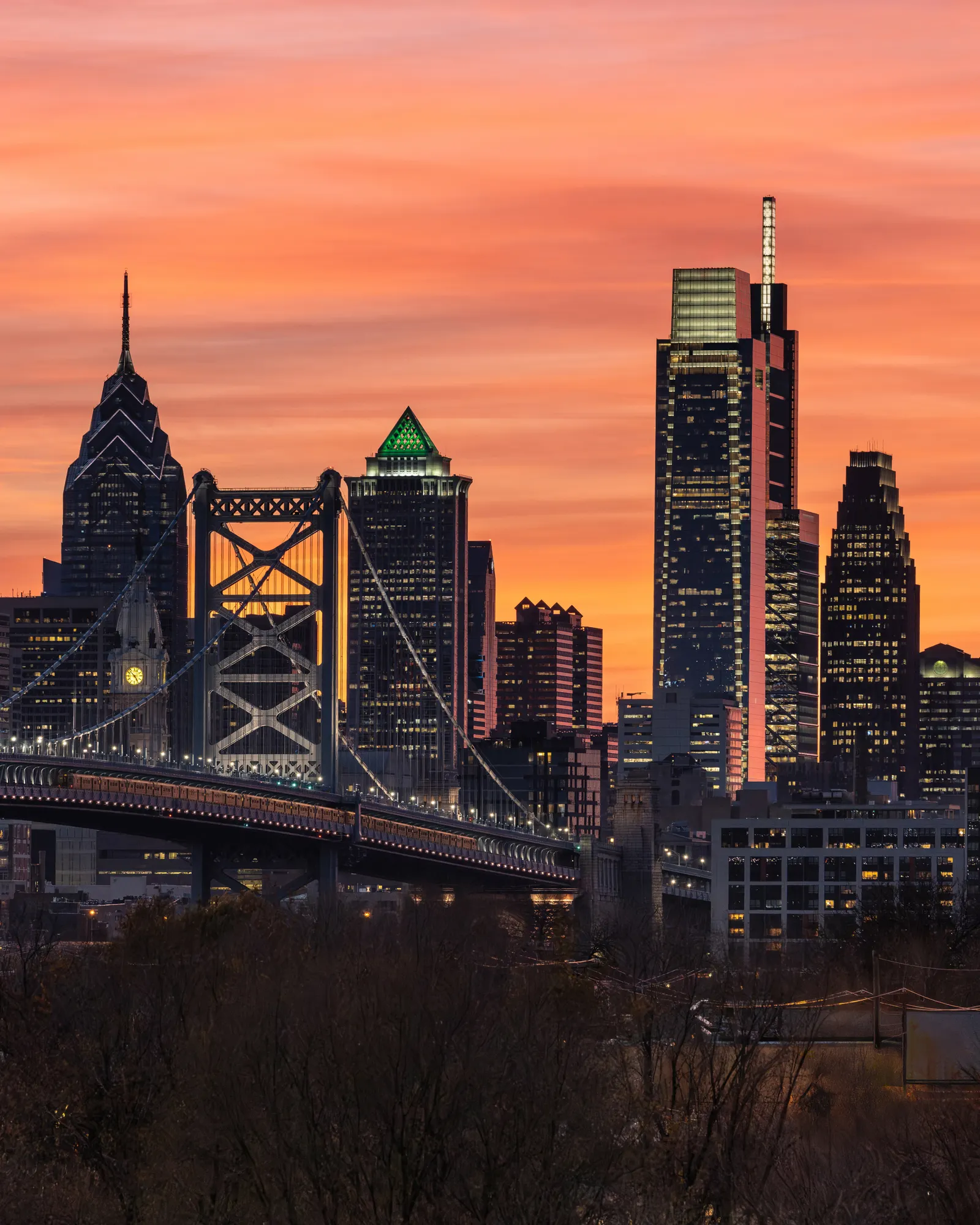 Philadelphia skyline and Benjamin Franklin Bridge glowing at sunset